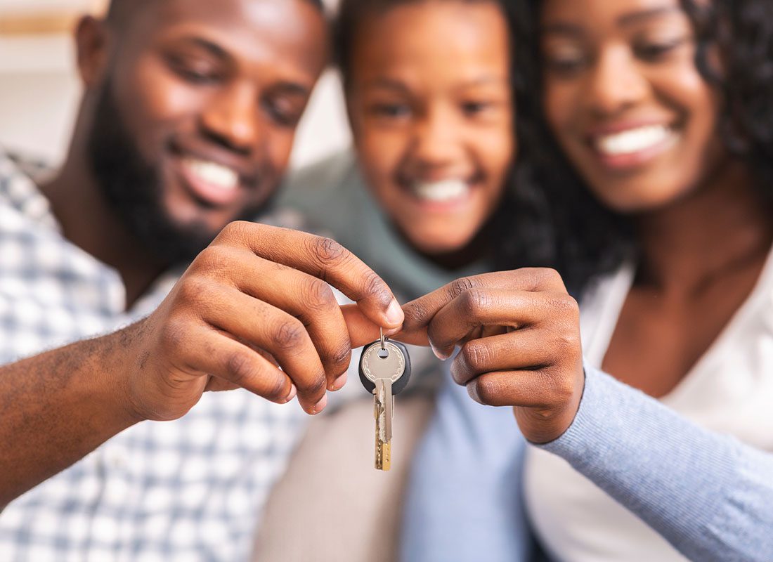 Insurance Solutions - Closeup of Family Smiling and Holding Keys to Their New Home